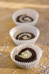 Party unbaked coffee anad coconut cookies in paper cupcakes on wooden bamboo table, shredded coconut