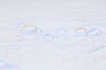 Bubbles in the white snow with a rainbow of colors and iridescent and translucent effects