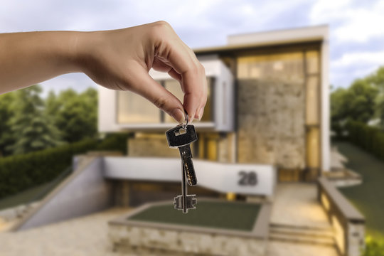 keys in hand, against a background of a blurred illustration modernist house, conceptual image