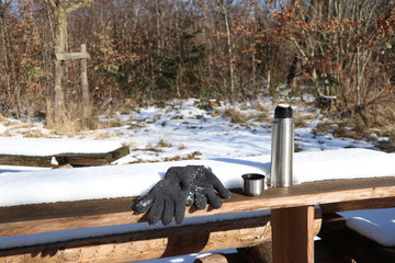 picnic scene with thermos cup and gloves