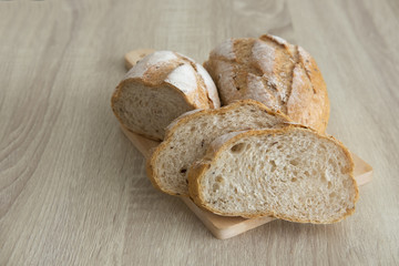 TWO CRUSTY SLICED BREAD ON CUTTING BOARD
Two brown crusty sliced french loaf on cutting board is placed on a wood table.