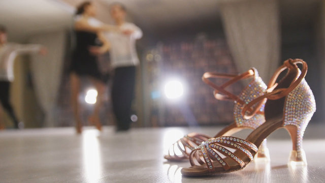 Blurred professional man and woman dancing Latin dance in costumes in the Studio, ballroom shoes in the foreground