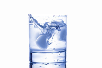 blue water splashing out of a glass with drops