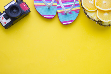 Bright yellow one-color background with slices of orange, old vintage camera and beach shoes, top view. Travel or tourism concept. Space for a text or product display.