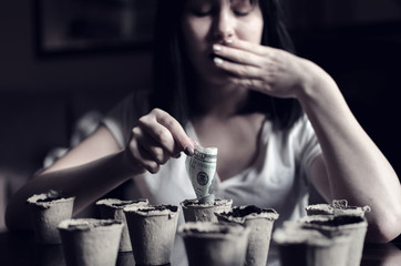 Young beautiful woman plant money in recycling pots