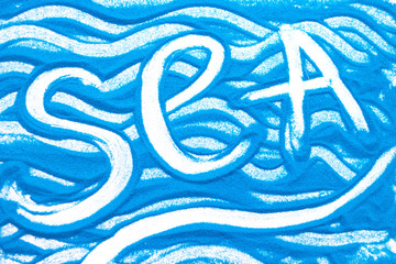 Sea inscription on a blue colored sand with waves, top view, flat lay