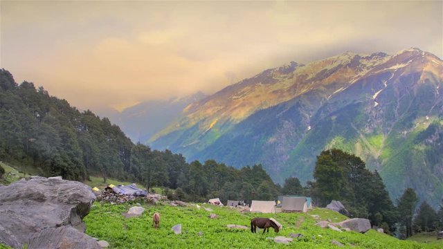 Time lapse of the trekkers strolling and horses grazing beside a beautiful campsite situated in the mountains