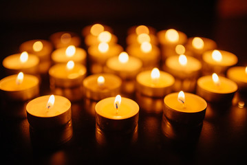 Burning candles. Shallow depth of field. Many christmas candles burning at night. Abstract candles background. Many candle flames glowing on dark background. Close-up.