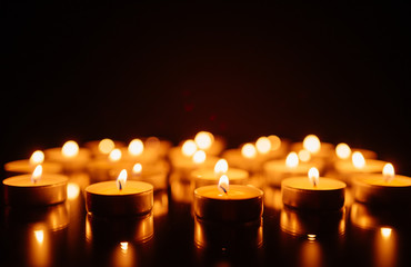 Burning candles. Shallow depth of field. Many christmas candles burning at night. Abstract candles background. Many candle flames glowing on dark background. Close-up. Free space.