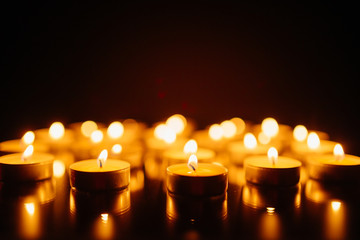 Burning candles. Shallow depth of field. Many christmas candles burning at night. Abstract candles background. Many candle flames glowing on dark background. Close-up. Free space.