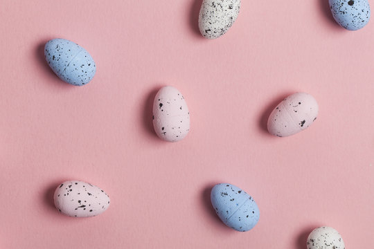 A collection of easter eggs on a pastel pink background