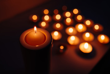 Burning candles. Shallow depth of field. Many christmas candles burning at night. Abstract candles background. Many candle flames glowing on dark background. Close-up.