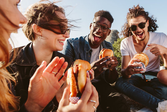 Group of friends eating burger on mountain top