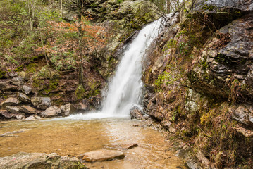 A beautiful waterfall is discovered and flows into a hidden canyon on a Spring day on a mountain.