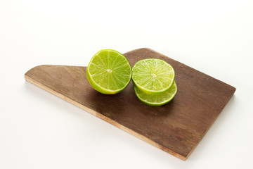 Fresh Lemon sliced on a wood cutting board with a knife on a white background