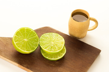 A shot of cachaca with lemon slices on a wood cutting board