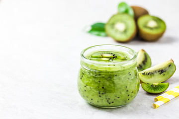 Kiwi puree in glass jar on white background. Selective focus, copy space. 