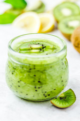 Kiwi green puree in glass jar on white background. Selective focus, copy space. 