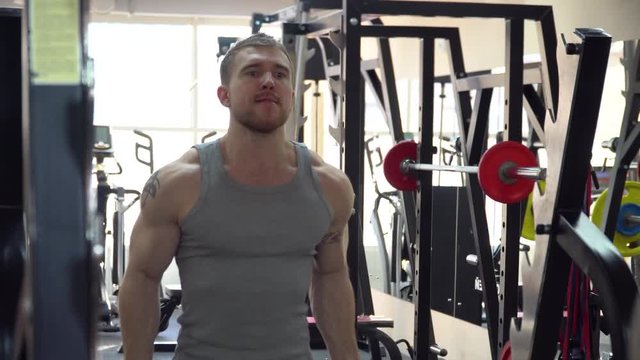 A sports guy trains in the gym, raises the bar to the biceps