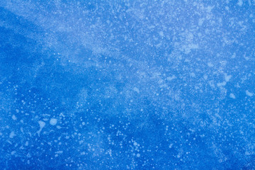 beautiful blue background of ice with cracks and bubbles 