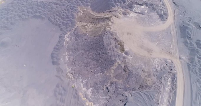 Vertical aerial shot over mine dumps showing truck loads as miniature bumps 4K