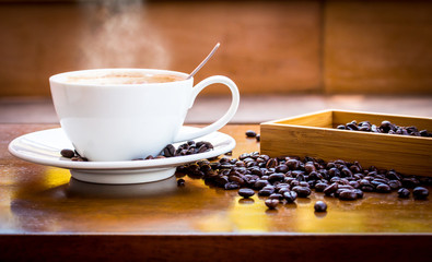 Coffee cup and coffee beans on table with smoke