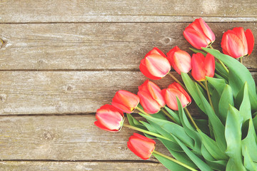 Row of bright rich red tulip flowers on stem. Wooden background with scopy text space. Welcome spring and summer. Mother's Day background, international woman's day greeting. Top view, flat lay.