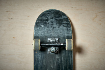 top view of black used skateboard on wooden background © superelaks
