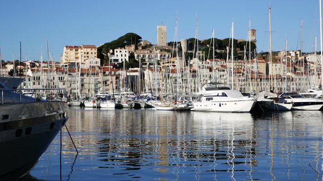Yachts moored in port of Cannes on background with residential district and medieval fortress