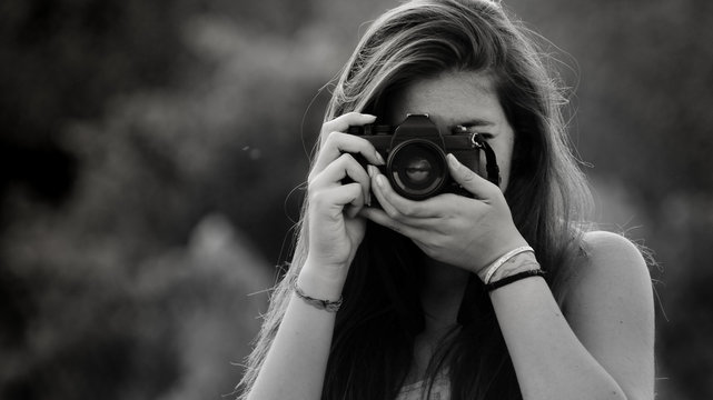 Ragazza che fotografa con macchina fotografica analogica vintage