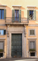 Building in Rome, details of old facade, wall with windows and wooden shutters.