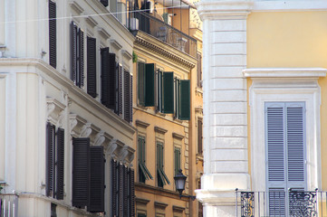 Building in Rome, details of old facade, wall with windows and wooden shutters.