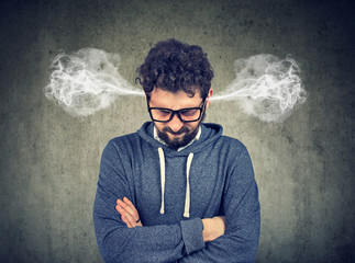 Angry young man, blowing steam coming out of ears, about to have nervous breakdown