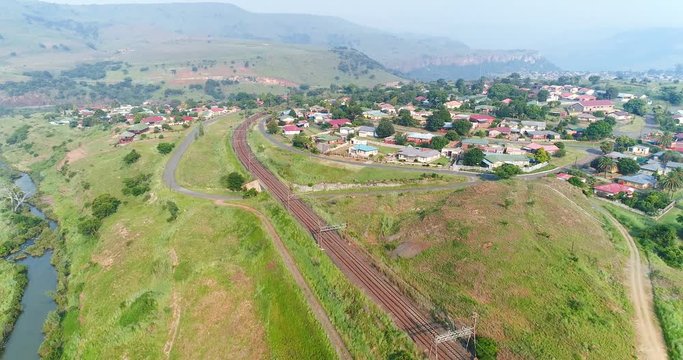 Establishing shot over small village town next to rail track in Waterval Boven South Africa 4K aerial