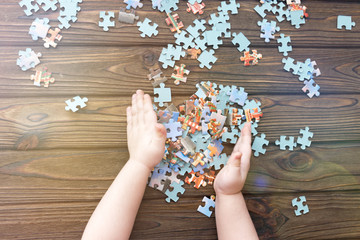 puzzles, the child's hands on the background of a wooden table. logical game. preschool education.