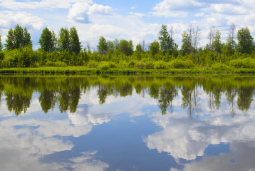 Fototapeta na wymiar Beautiful summer landscape with reflection of clouds in the river
