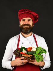 Chef holds lettuce, tomato, pepper and mushrooms.