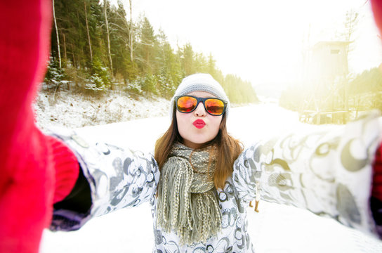 beautiful young woman taking a selfie in winter nature. Pretty woman taking a photo in a nature. Winter background. 