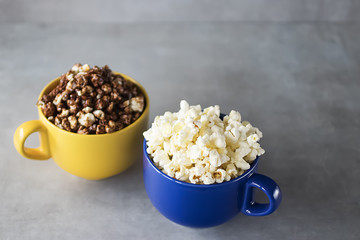 Popcorn in yellow and blue bowls on a gray background.