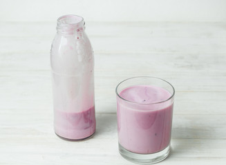 Yogurt in a glass and a bottle on a white background.