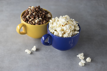 Popcorn in yellow and blue bowls on a gray background.