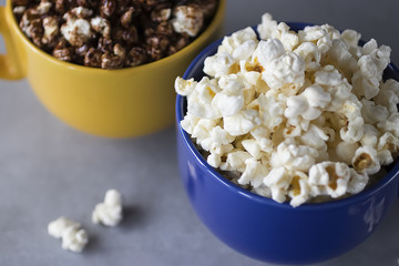 Popcorn in yellow and blue bowls on a gray background.