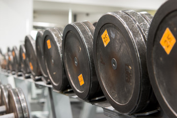 Set of old and used weights, dumbbells on a rack in a gym. Workout equipment