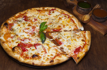 pizza with cheese and tomatoes with a sprig of basil