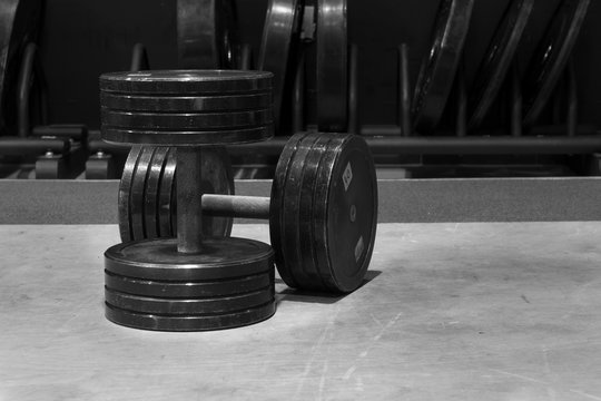 Used and old black gym dumbbells, black and white image, photo.