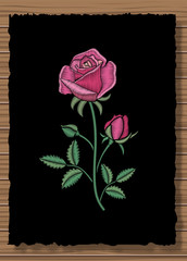 Floral stitched ornament with stitch rose. Embroidery flower on a dark flap cloth and wooden texture background.