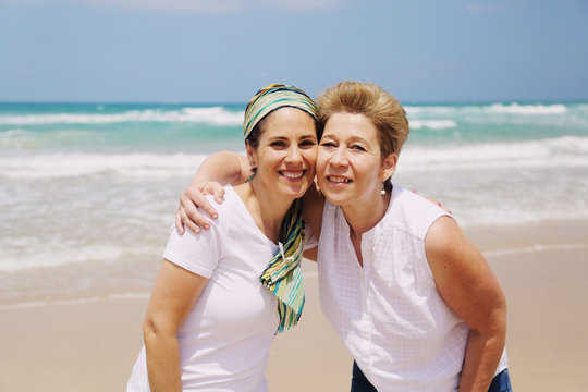 Portrait of two beautiful 45 years old women walking on seaside