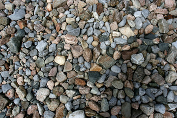 Many small multicolor stones on a sea coast.