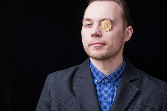 young businessman holds an eye with a gold coin bitkoin