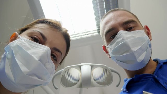 doctor and assistant in medical masks close-up during visit of customer, patient point of view
